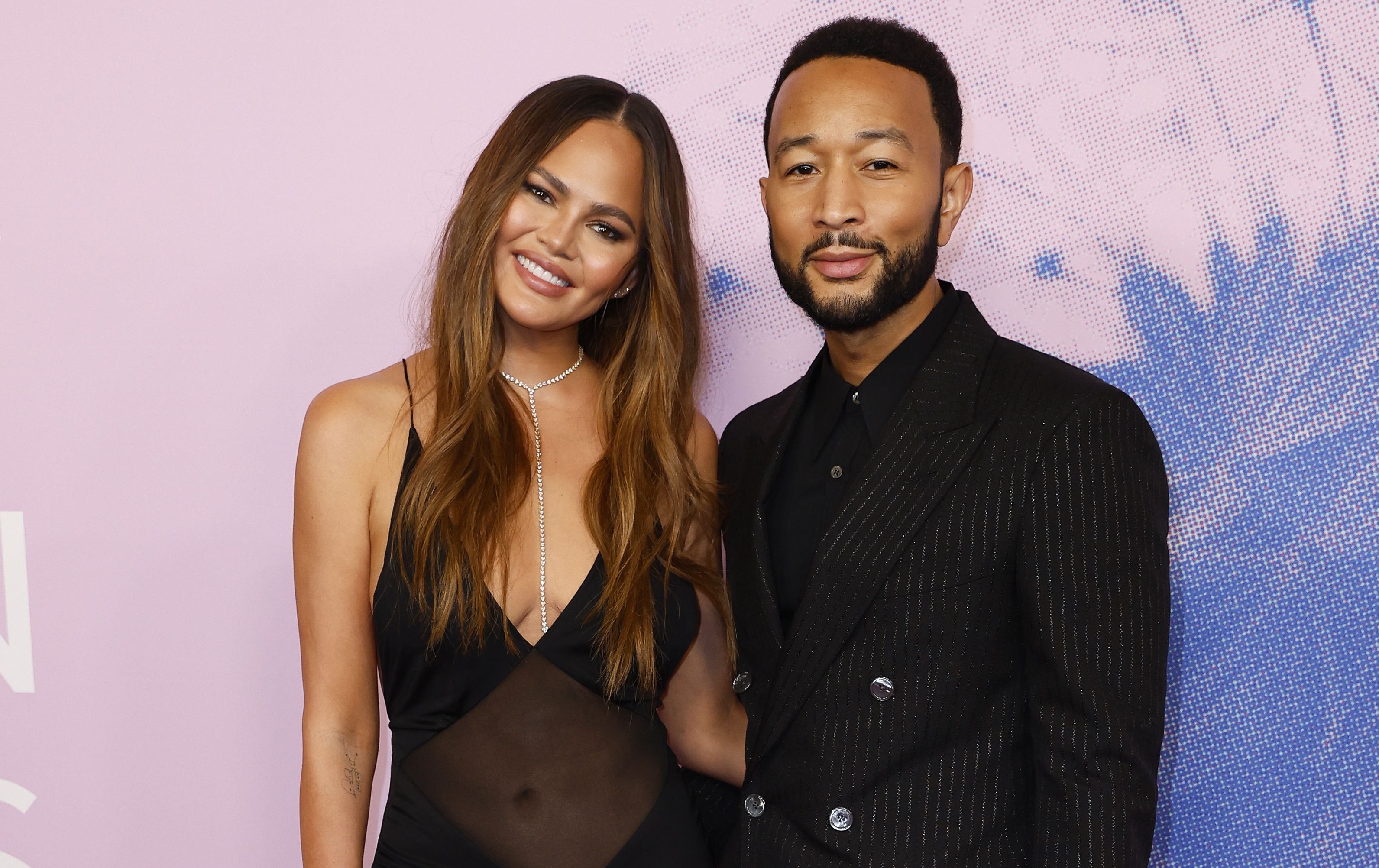 John Legend looks sharp in pinstripes at the Green Carpet Fashion Awards, while his wife Chrissy Teigen's thin outfit gets the fever rising